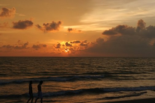 couple walking on beach at sunset